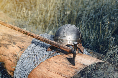 Metal chain mail, helmet and ax lie on wooden log. viking armor. historical film concept.