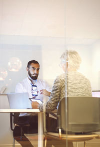 Young businessman giving presentation to female colleague on mobile phone in office