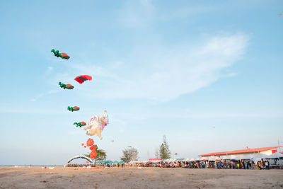 Multi colored balloons flying on beach against sky