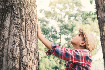 Boy touching tree trunk