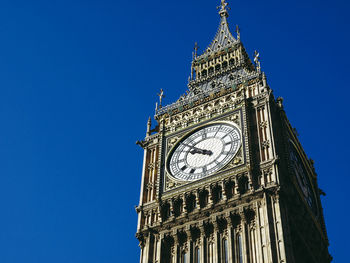 Low angle view of clock tower against blue sky