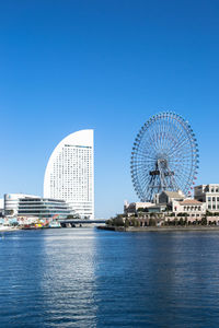 Ferris wheel in city against clear blue sky