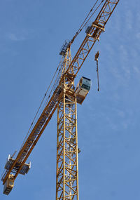 Low angle view of crane against blue sky