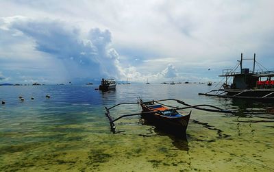 Boats in sea against cloudy sky