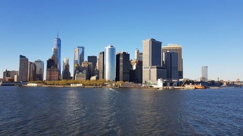 Sea by modern buildings against clear sky