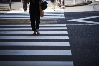 Low section of woman standing on zebra crossing