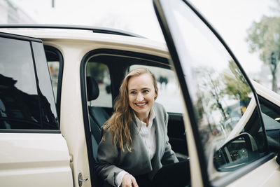 Smiling female entrepreneur getting out of taxi during business trip