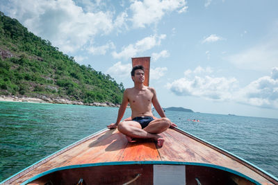 Man sitting on boat in sea against sky