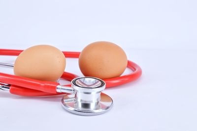 Close-up of eggs and stethoscope on white background