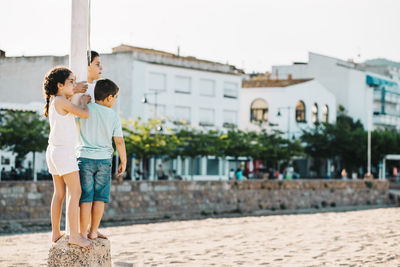 Rear view of friends with son on umbrella against buildings