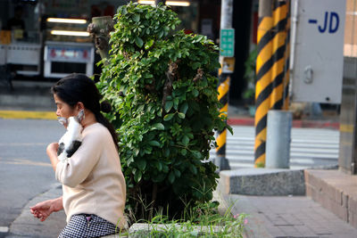 Side view of woman standing against plants