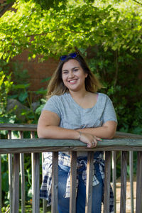 Portrait of smiling woman standing by railing 