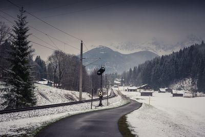 Snow covered road by mountains against clear sky