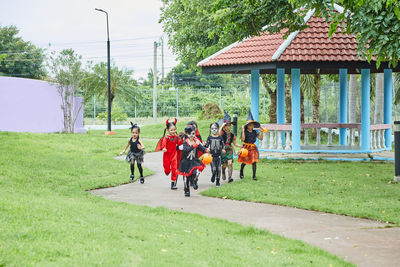 Girls in halloween costumes running on footpath at park