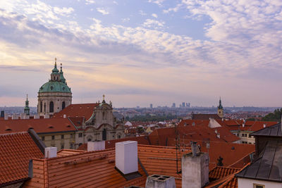 Prague, st. nicholas cathedral and red tiled roofs of houses in early morning at sunrise, beautiful 