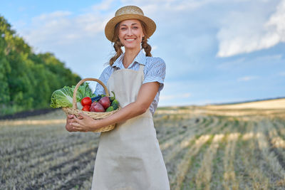 Portrait of a smiling young woman standing on field