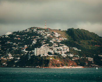 Scenic view of sea by buildings against sky