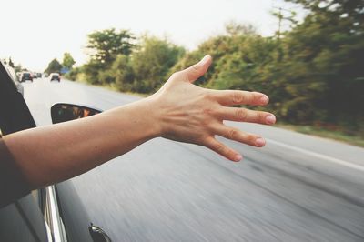 Cropped image of man hand coming out from car window against clear sky