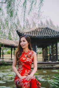 Young woman standing against red wall