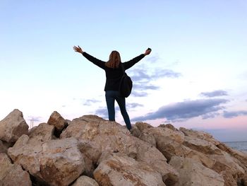 Full length of woman standing on rock against sky