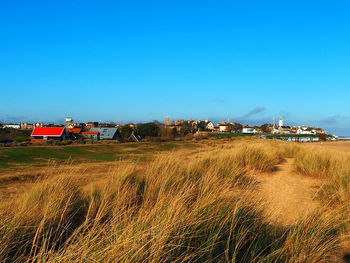 Houses on field against clear blue sky