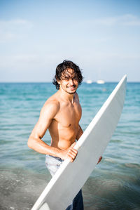 Full length of shirtless man in sea against sky