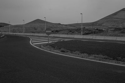 Empty road leading towards mountain against sky