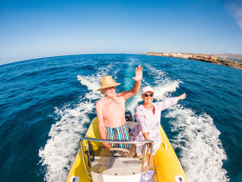 People on boat in sea against sky