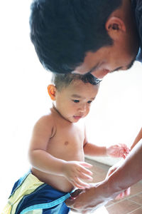 Man undressing son against white background