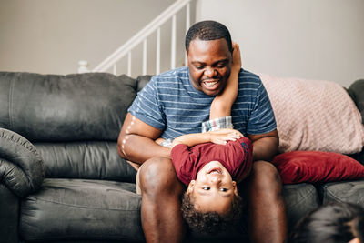 Father and kids at home playing on couch, african american or black father with his children enjoy