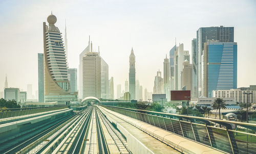 Railroad tracks amidst buildings in city against sky