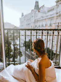 Side view of young woman looking through window