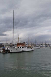 Boats moored in calm sea against cloudy sky