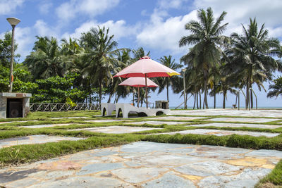 Built structure by palm trees on beach against sky