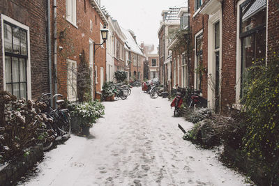 Frozen footpath amidst buildings against sky