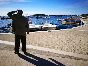Rear view of man looking at sea during sunny day