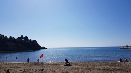 People on beach against clear sky