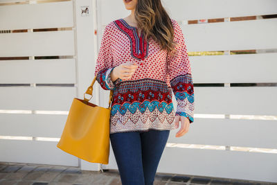 Midsection of woman standing against wall