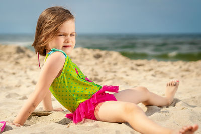Midsection of baby girl sitting on beach