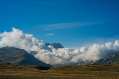 Scenic view of field and mountains against blue sky