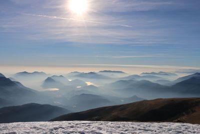 Scenic view of snow covered field and mountains range against sky