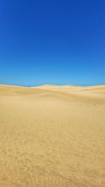 Scenic view of desert against clear blue sky