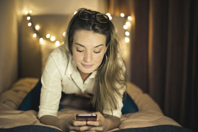 Young woman on a bed with a smartphone