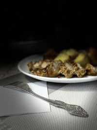 Close-up of food in plate on table against black background