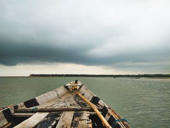 Boat on lake against cloudy sky