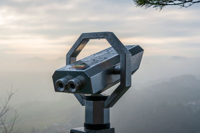 Close-up of coin-operated binoculars against sky