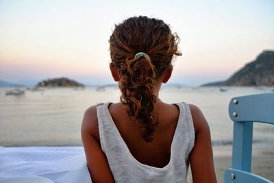 Rear view of girl sitting at beach