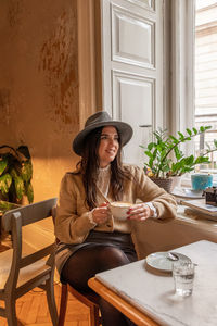 Portrait of woman using mobile phone while sitting on table