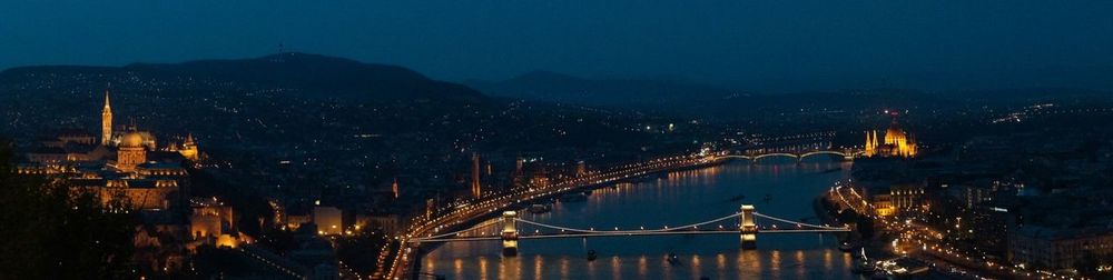 Illuminated bridge over river at night