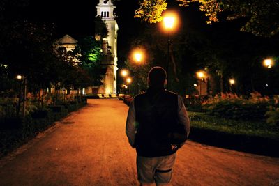 Rear view of man walking on road at night